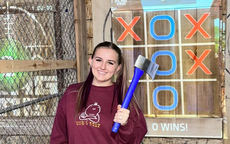 Girl holding and axe in front of digital projected target